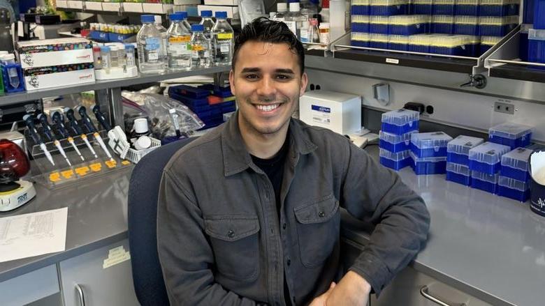 Erick Astacio surrounded by laboratory equipment